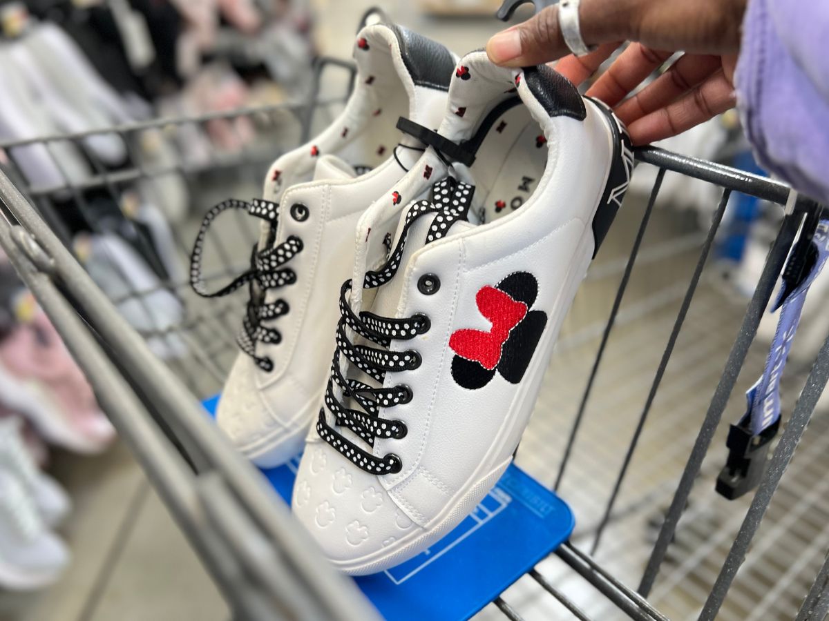 a pair of womens white low top lace up sneakers in the front basket of a shopping cart
