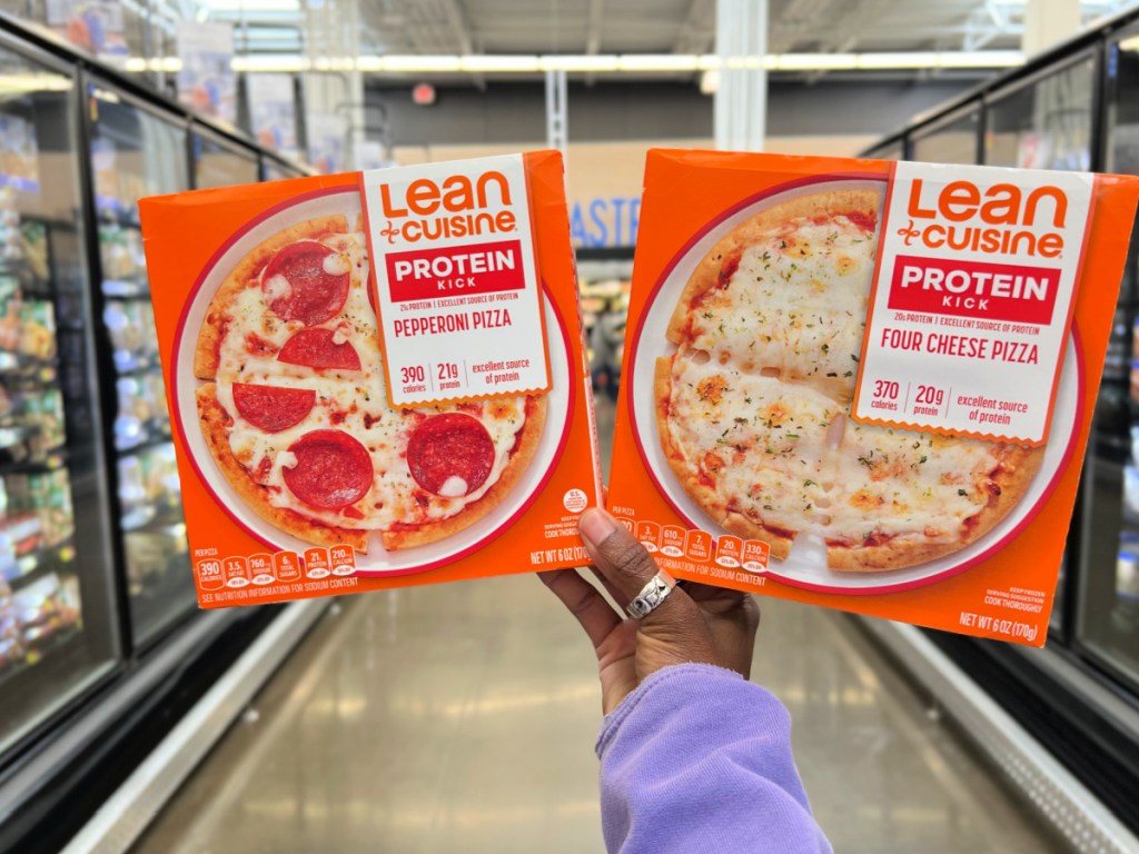 Person holding up boxes of lean cuisine pizzas in the freezer aisle in Walmart.