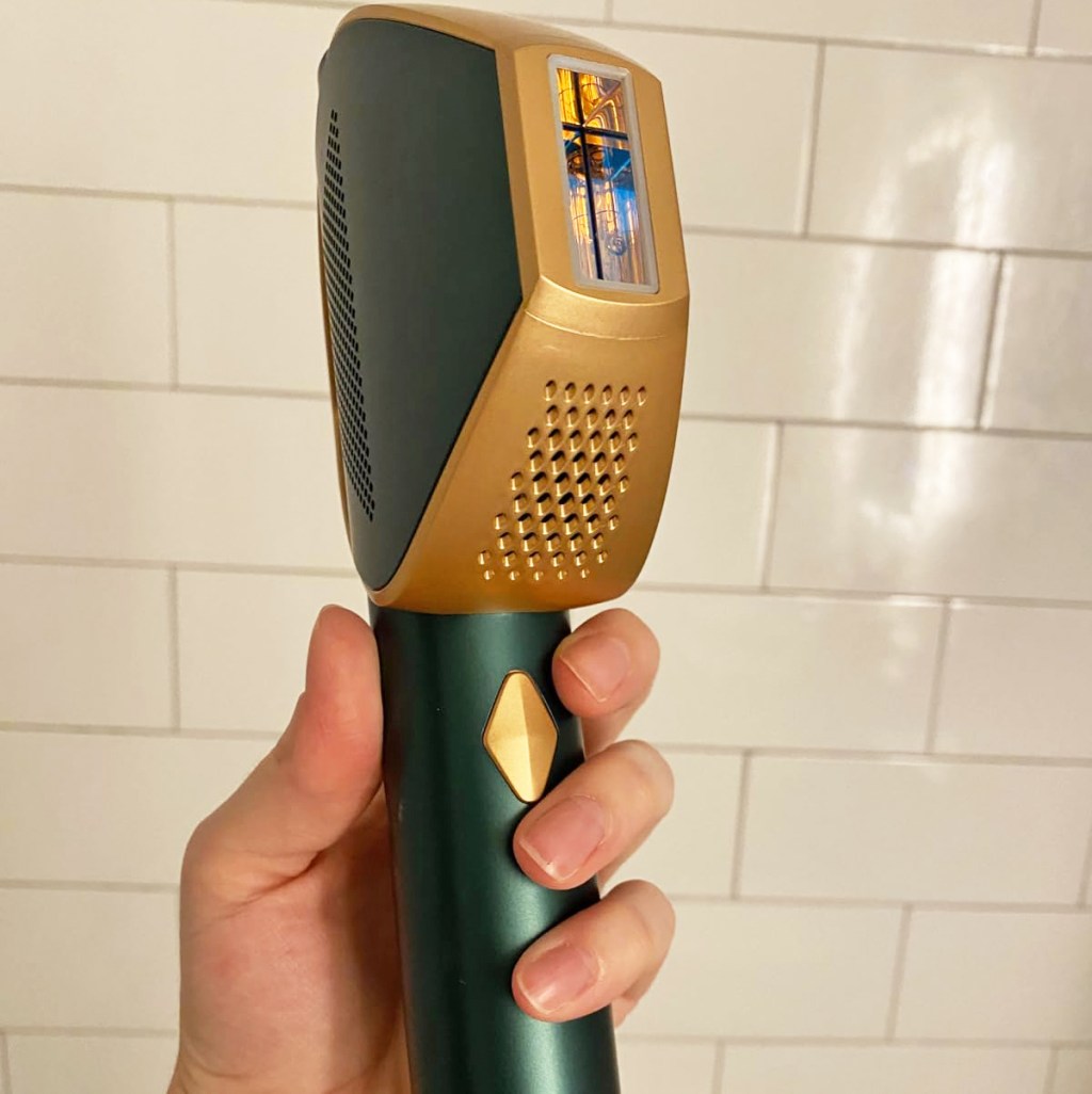 hand holding up a green and gold IPL device