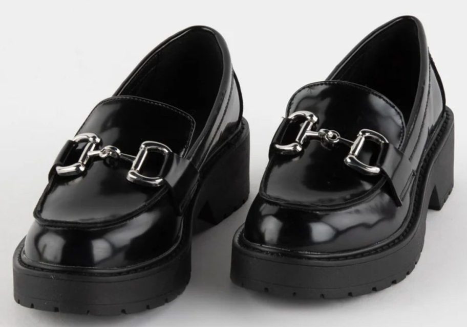 a pair of black heeled loafers with silver bucles