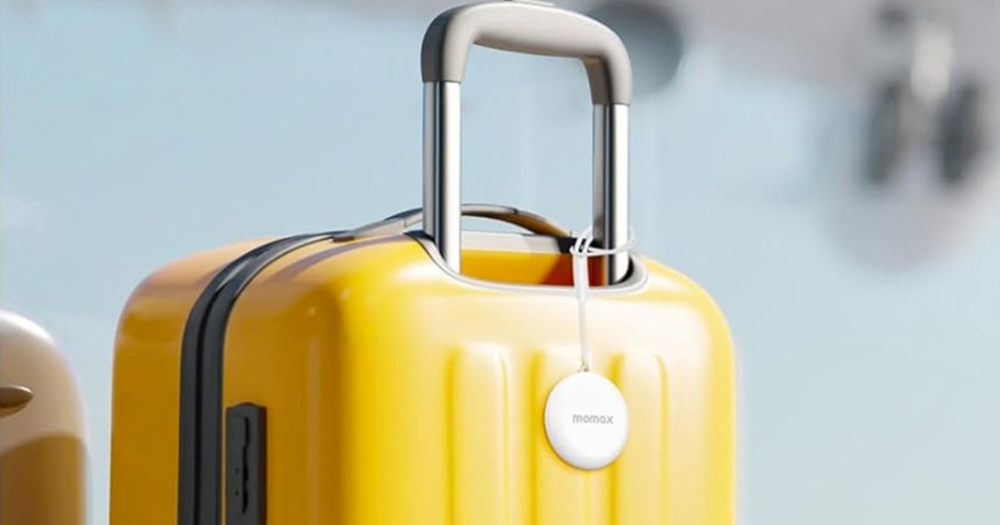 white tracker tag hanging on a yellow suitcase