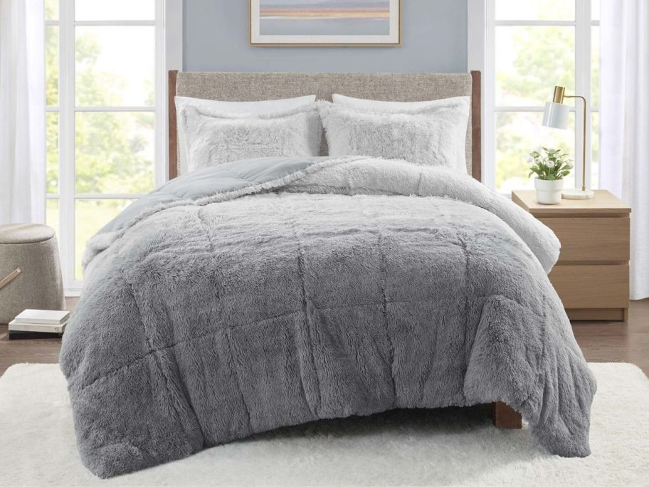 a grey faux fur comforter set on a queen bed