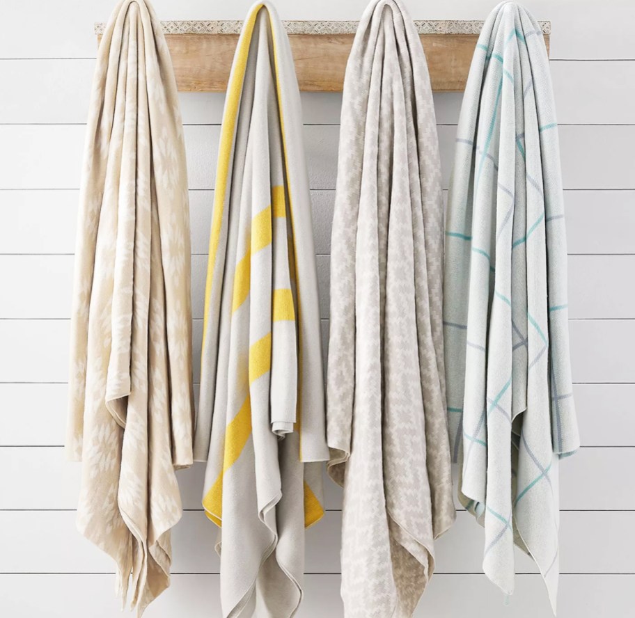four printed throw blankets hanging on wall hooks