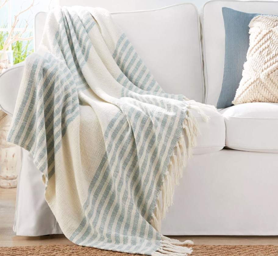 white and blue striped blanket with tassels draped over couch