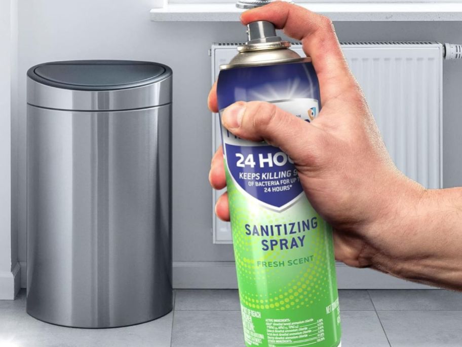 Hand spraying Microban on a trash Can