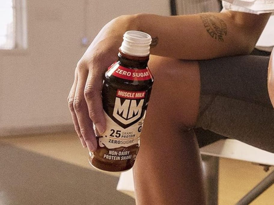 An athlete holding a bottle of Muscle Milk Chocolate 