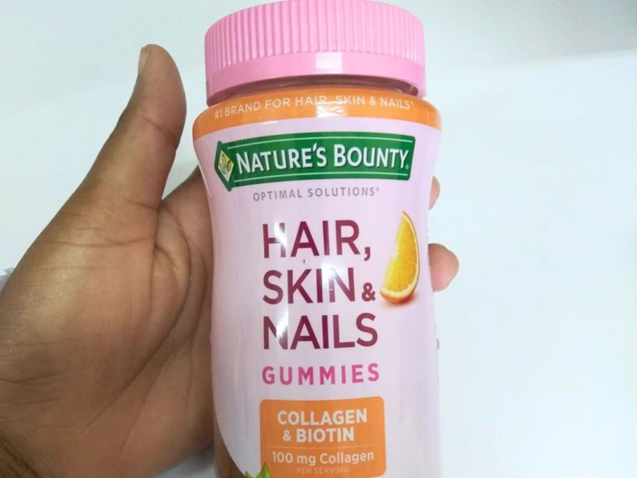 Hand holding a bottle of Nature's Bounty Hair Skin and Nails gummies
