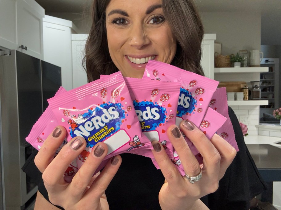 Woman holding up Nerds Gummy Cluster treat bags for classroom exchanges