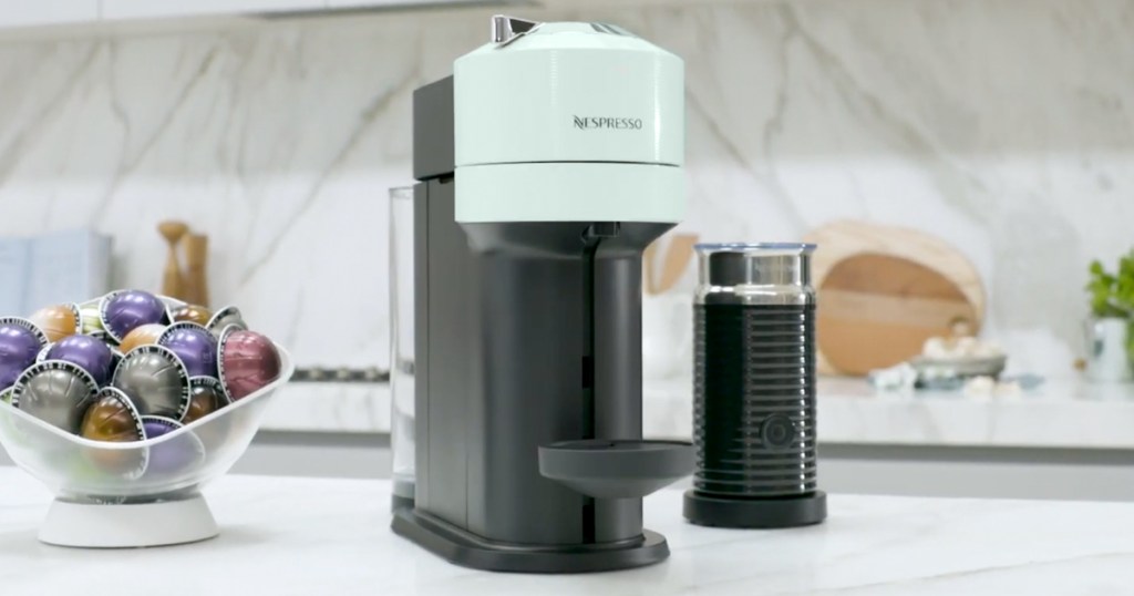 nespresso machine on kitchen counter near bowl of capsules and milk frother