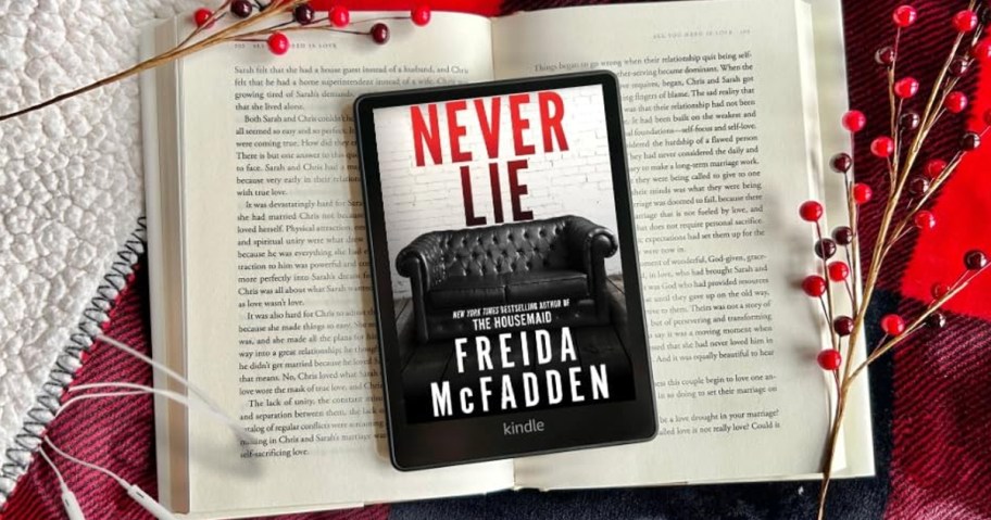 Never Lie book on Kindle device sitting on top of an opened book