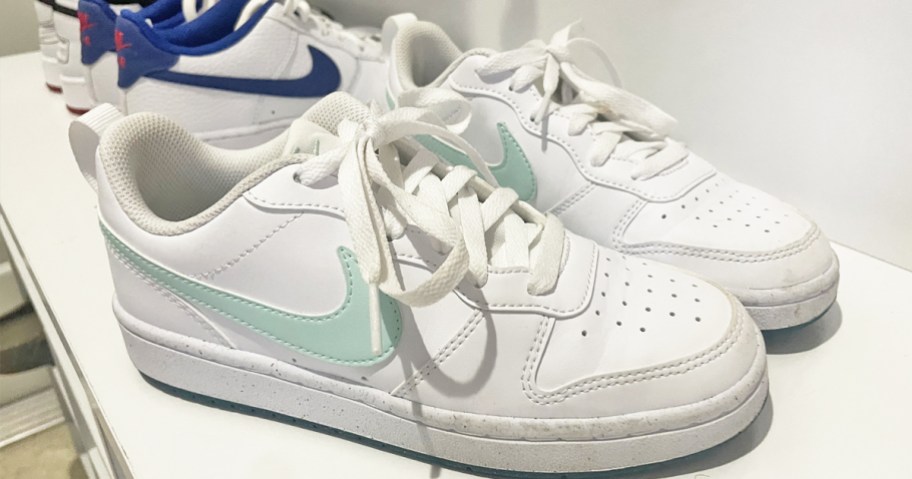 pair of white and mint green nike sneakers on a white bench