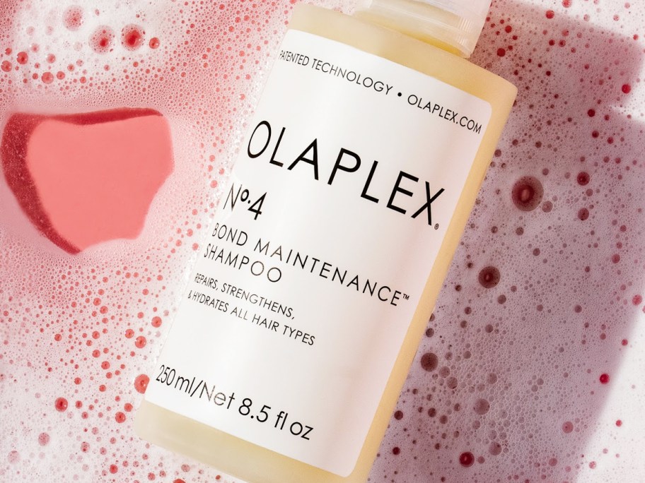 bottle of Olaplex No. 4 Bond Maintenance Shampoo in pink soapy water