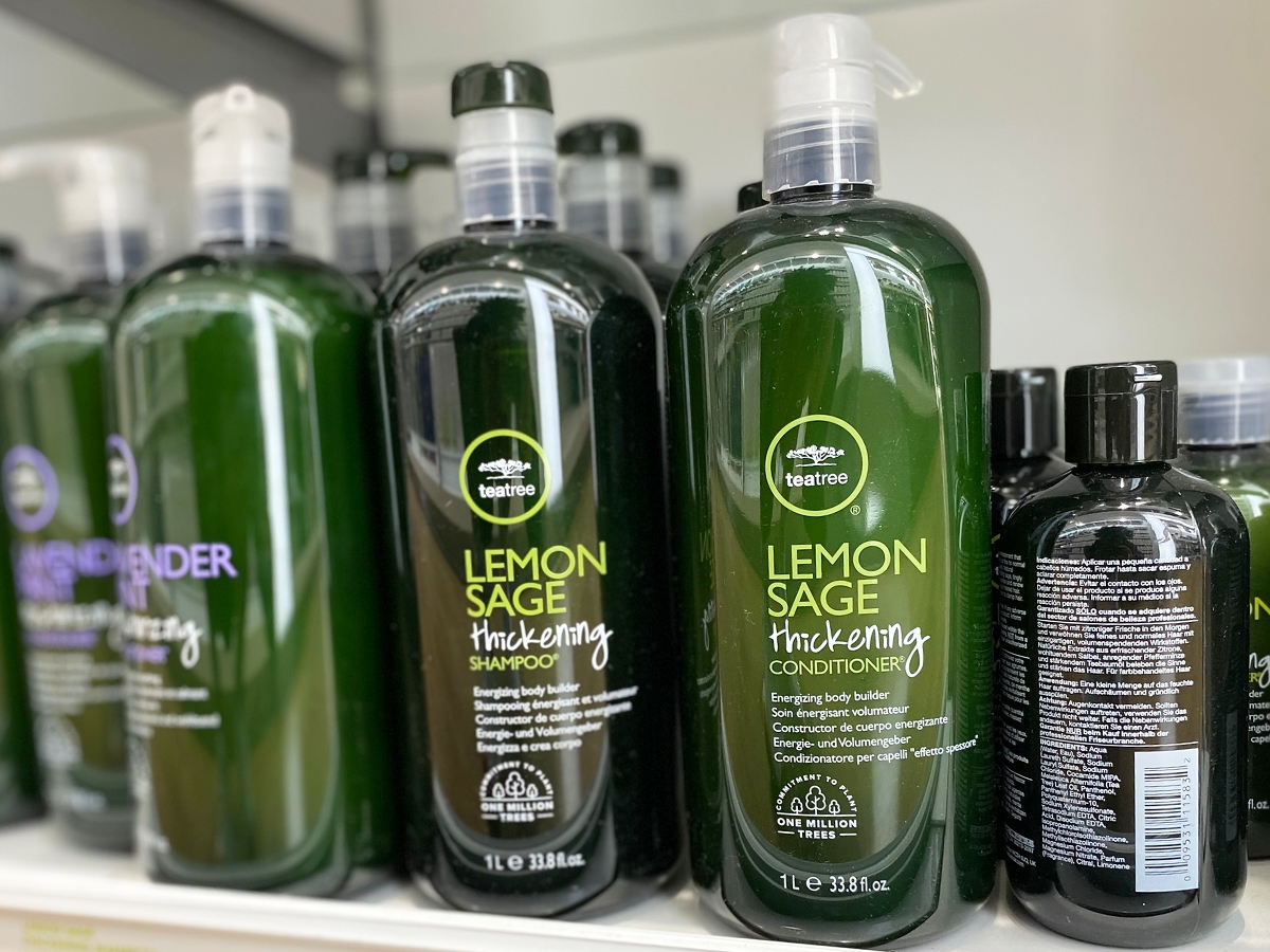 green liter bottles of Paul Mitchell Tea Tree Shampoo & Conditioner on store shelf