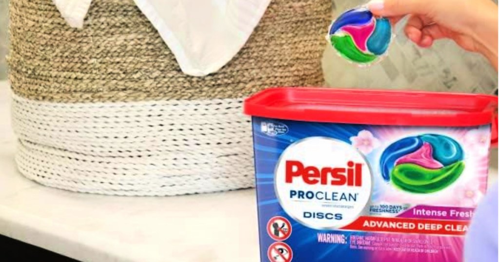 Persil Discs Laundry Detergent Pacs in Intense Fresh 62 count pack on counter by laundry basket