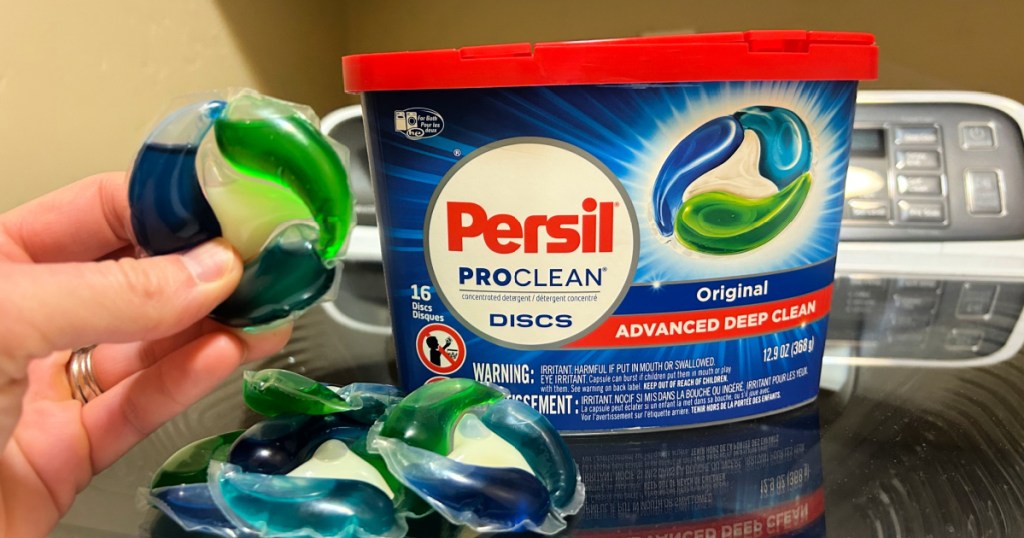 person holding persil detergent tabs in front of container on washing machine