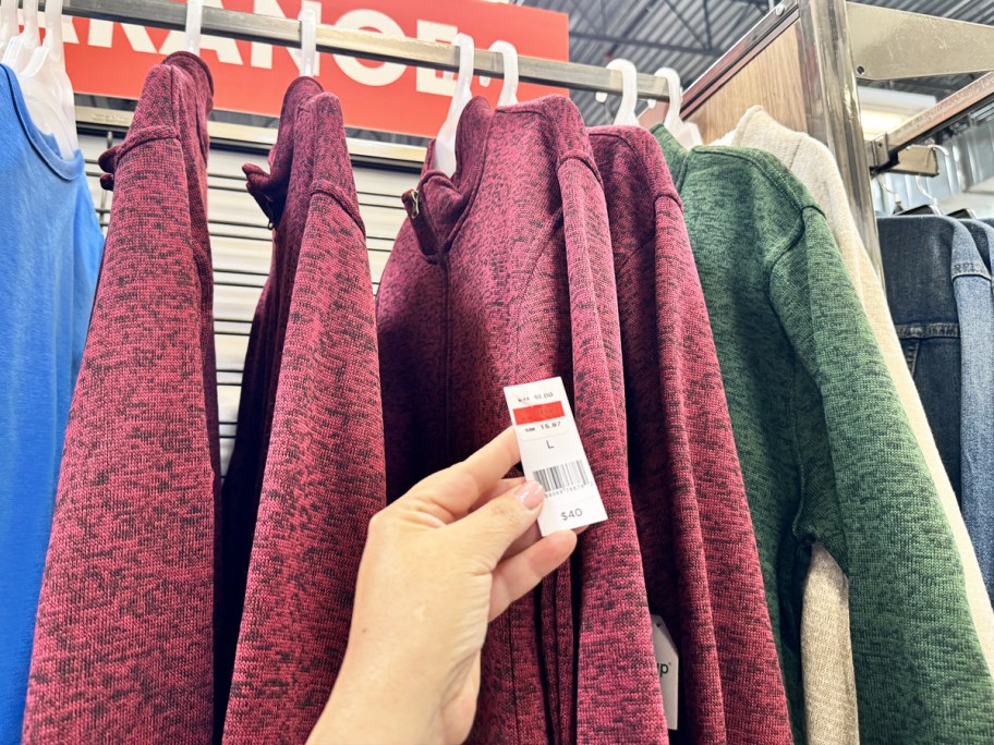 hand holding price tag from a red pullover sweater
