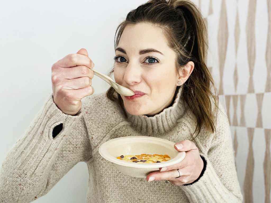 woman eating cereal out of disposable bowl with matching spoon