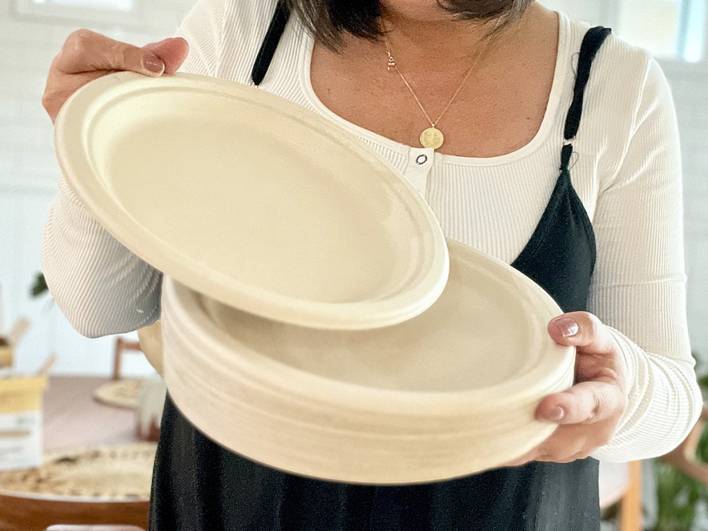 woman holding up a stack of disposable plates