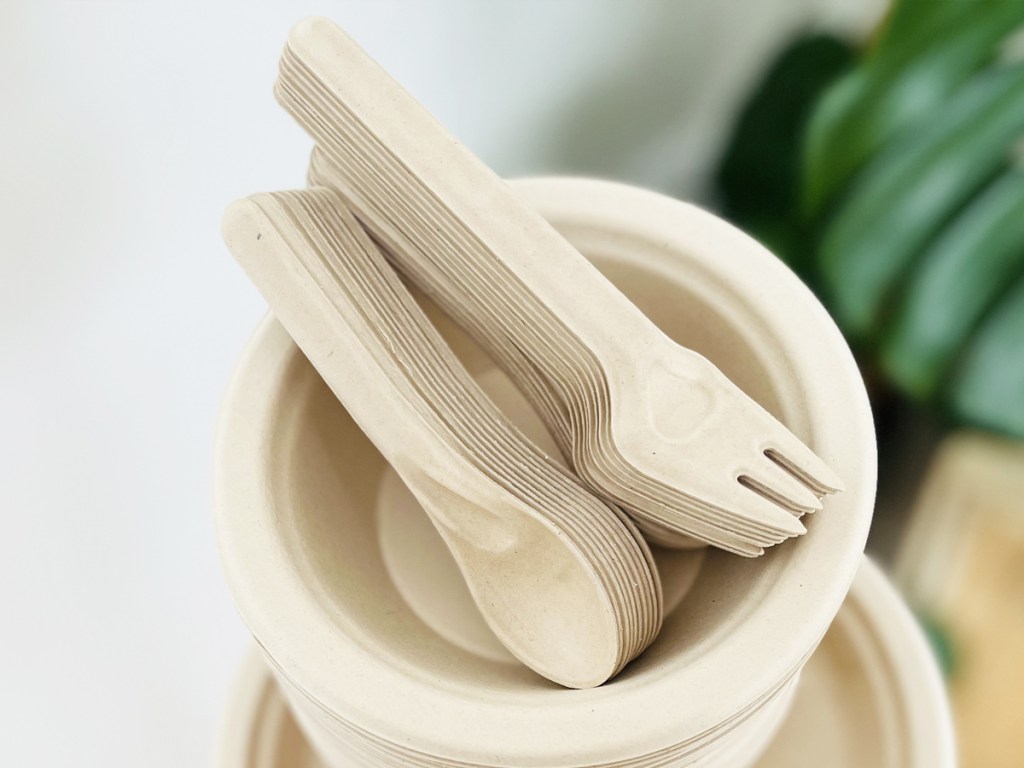 disposable fiber spoons and forks on top of a stack of matching bowls