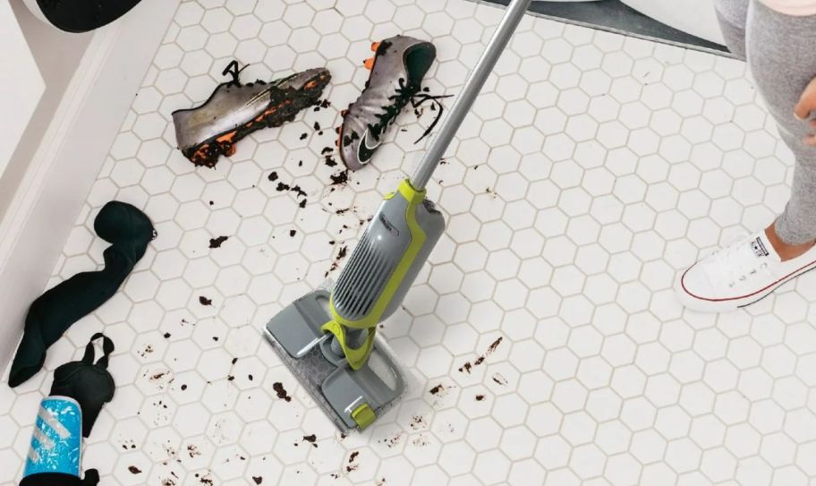 a shark vacmop cleaning up a muddy mess on a white tile floor