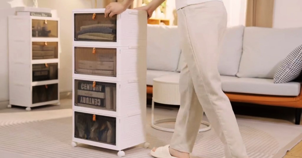 Woman pushing white stackable bins across the living room floor