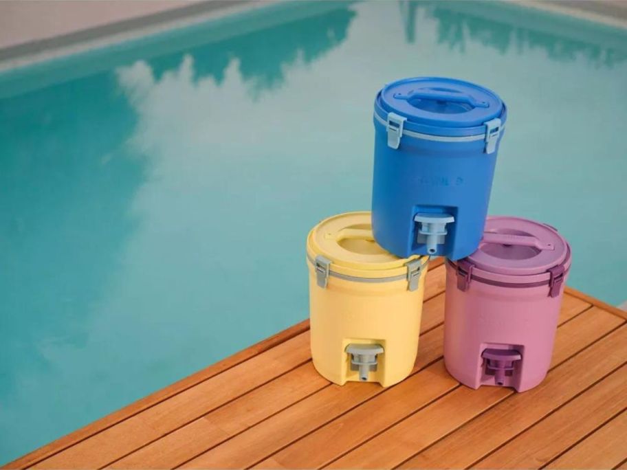 blue yellow and purple water jugs on deck next to pool