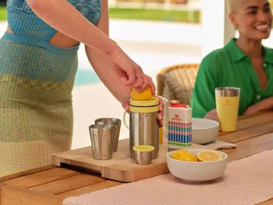 woman purring lemon into stainless steel Stanley cocktail shaker