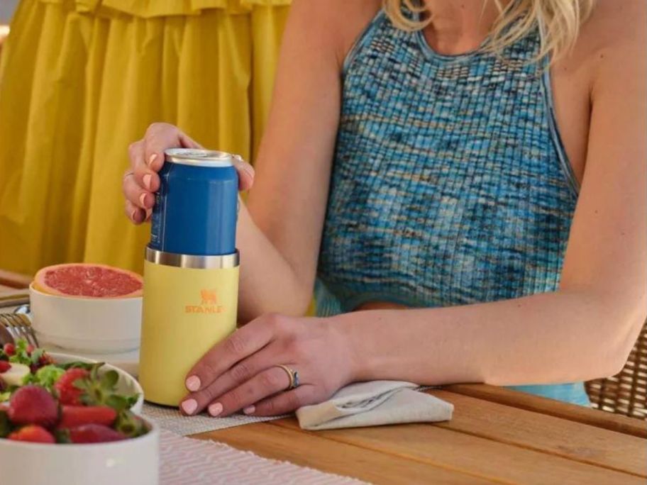 woman putting drink into yellow Stanley can cooler