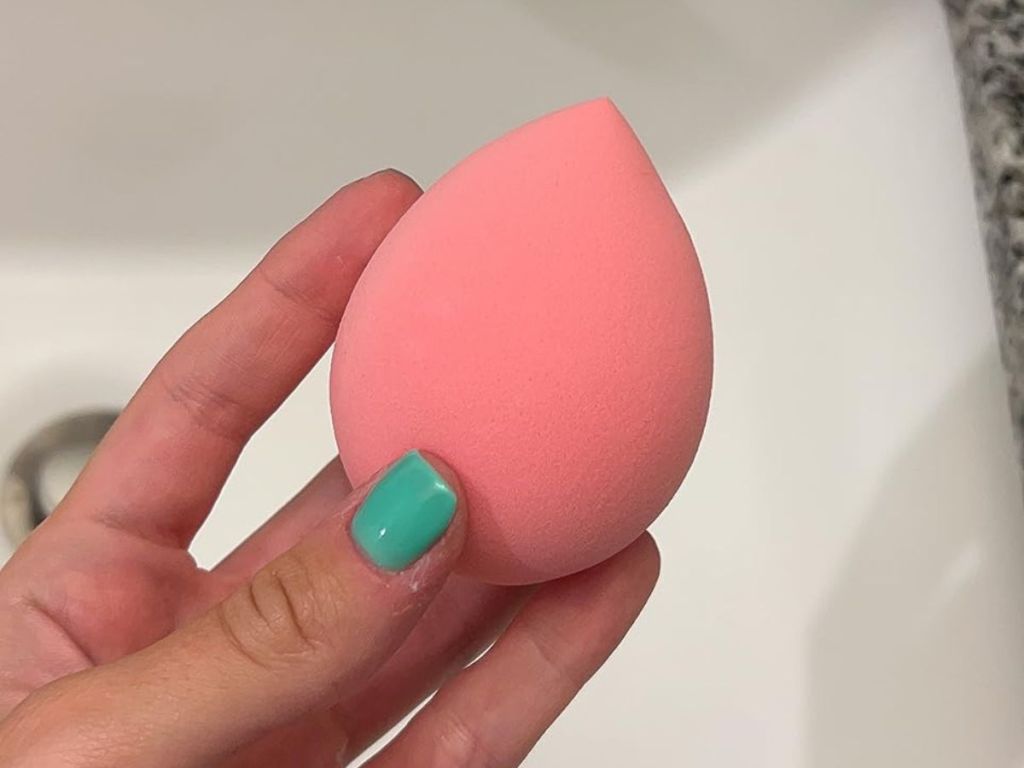 A hand holding a makeup sponge