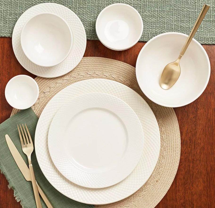 white dinnerware set arranged on table with gold utensils