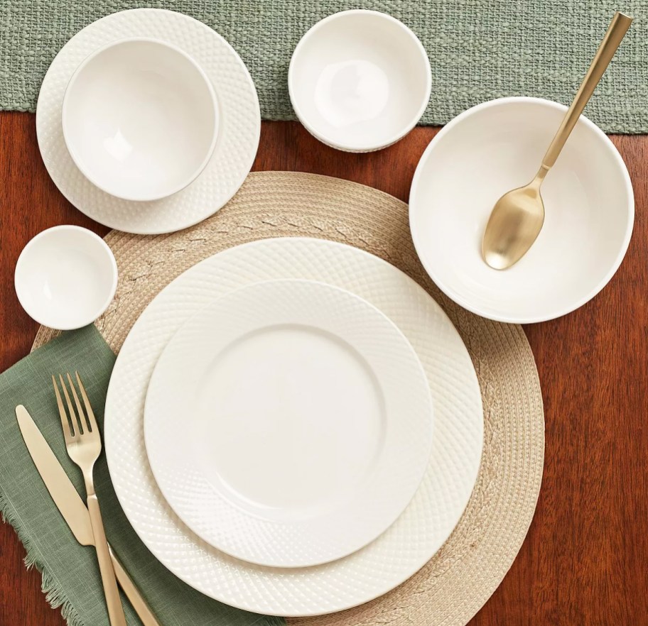 white dinnerware set arranged on table with gold utensils