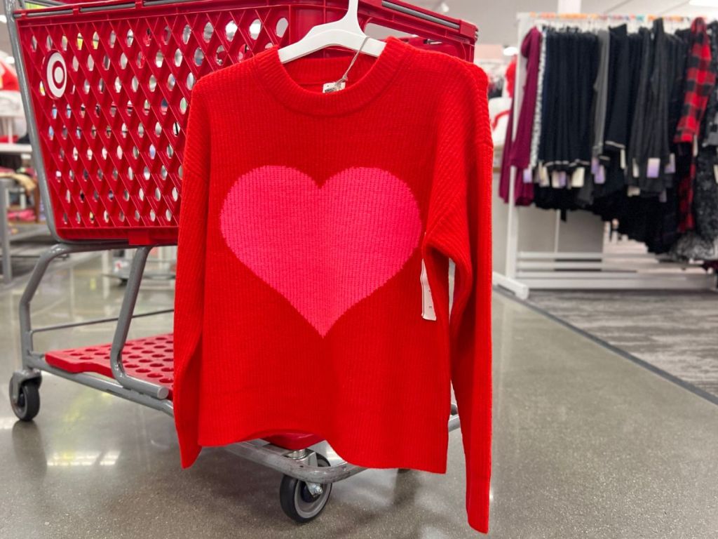 women's red sweater with large pink heart hanging on cart at Target
