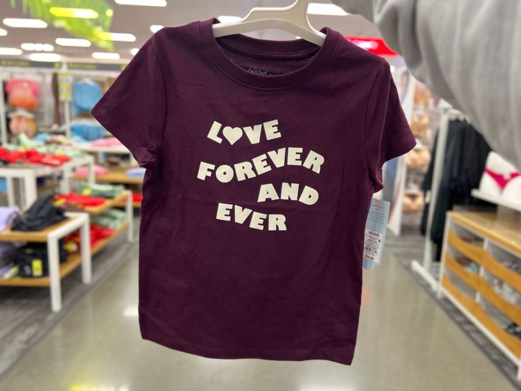 hand holding up a kid's purple burgundy color graphic tshirt that says "Love Forever and Ever"