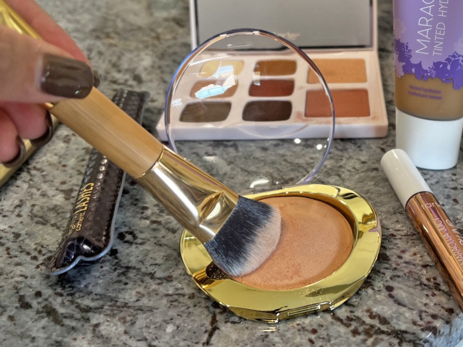 woman dipping brush into bronzer