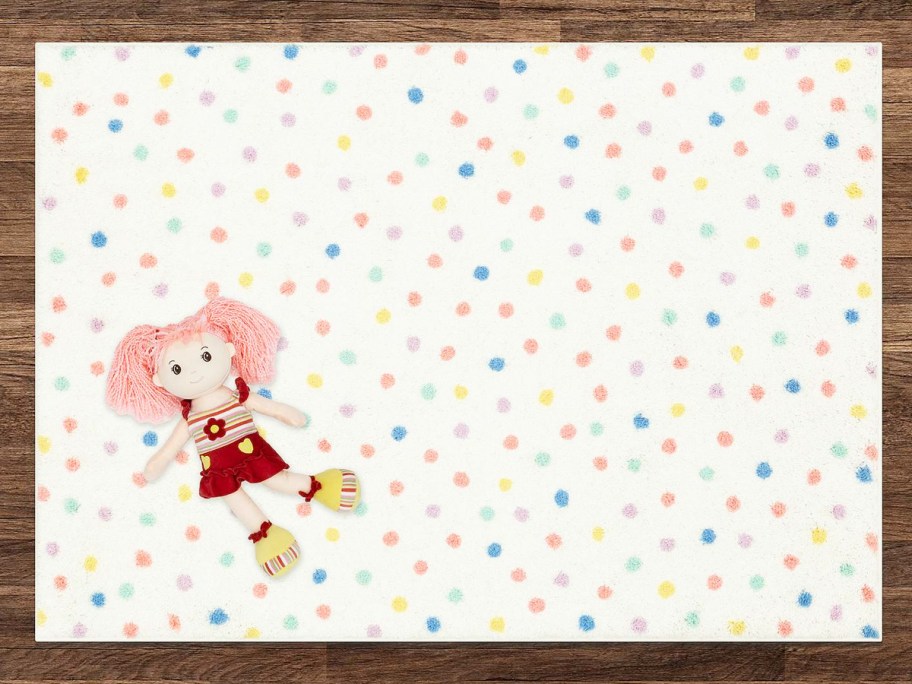 doll laying on a multi-color polka dot print rug