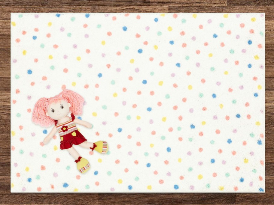 doll laying on a multi-color polka dot print rug
