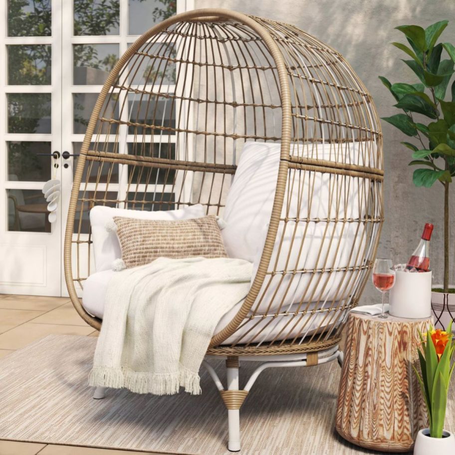 a wicker egg chair with linen cushions on a patio