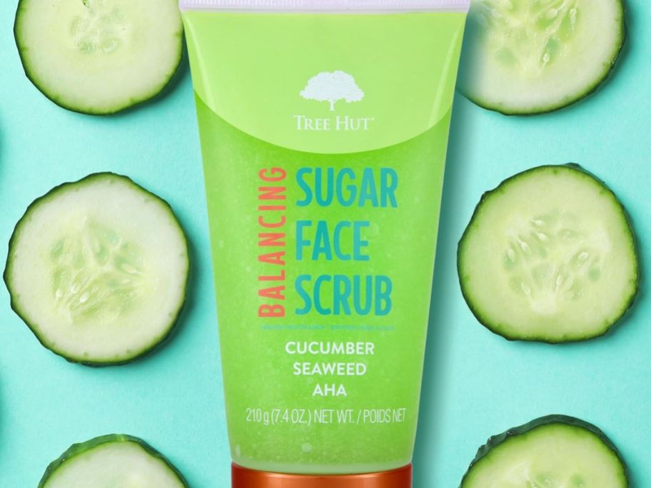 A tube of Tree Hut Balancing Sugar Face Scrub with cucumbers in the background