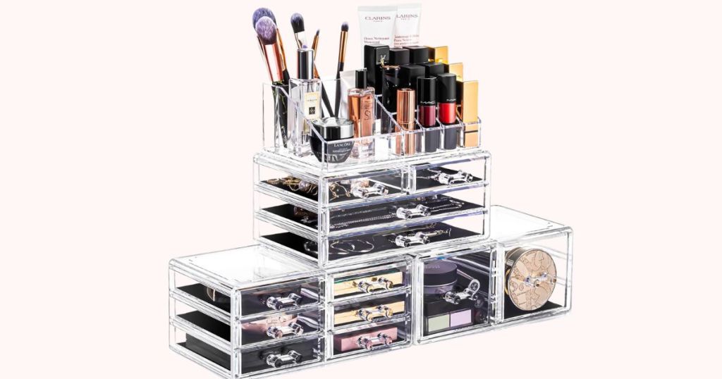 a four piece acrylic jewelry organizer stacked in 3 tiers and filled with a range of cosmetics, from lipstick tubes to eyeshadow palettes 