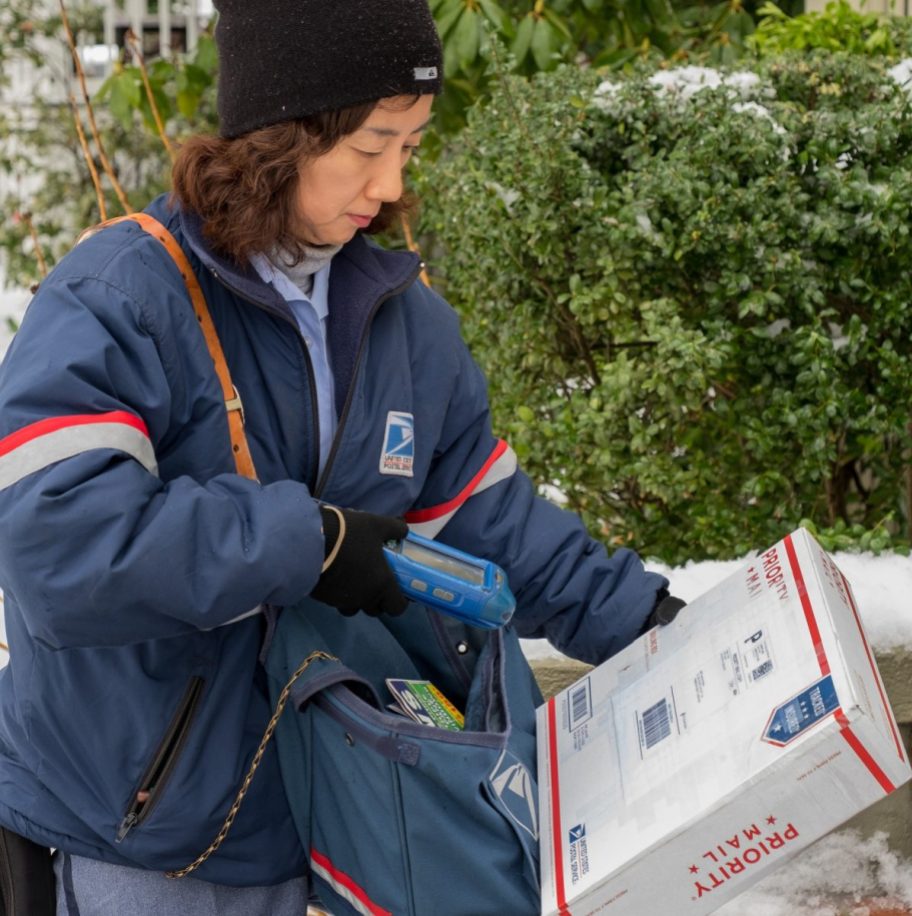 A USPS postal worker delivering priority mail