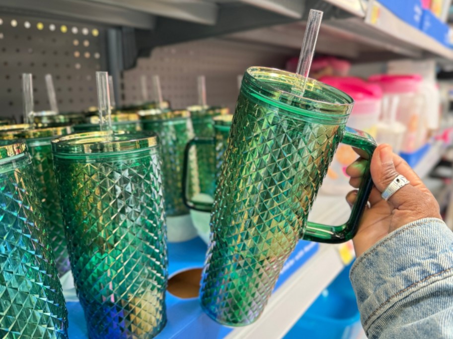 hand holding a green and blue studded iridescent large tumbler with handle with more beside it