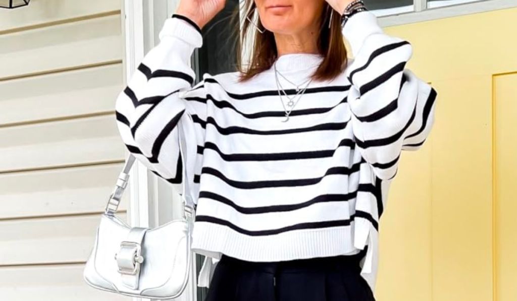 a women stepping out her front door waering the Women’s Crew Neck Striped Cropped Sweater in white with black stripes