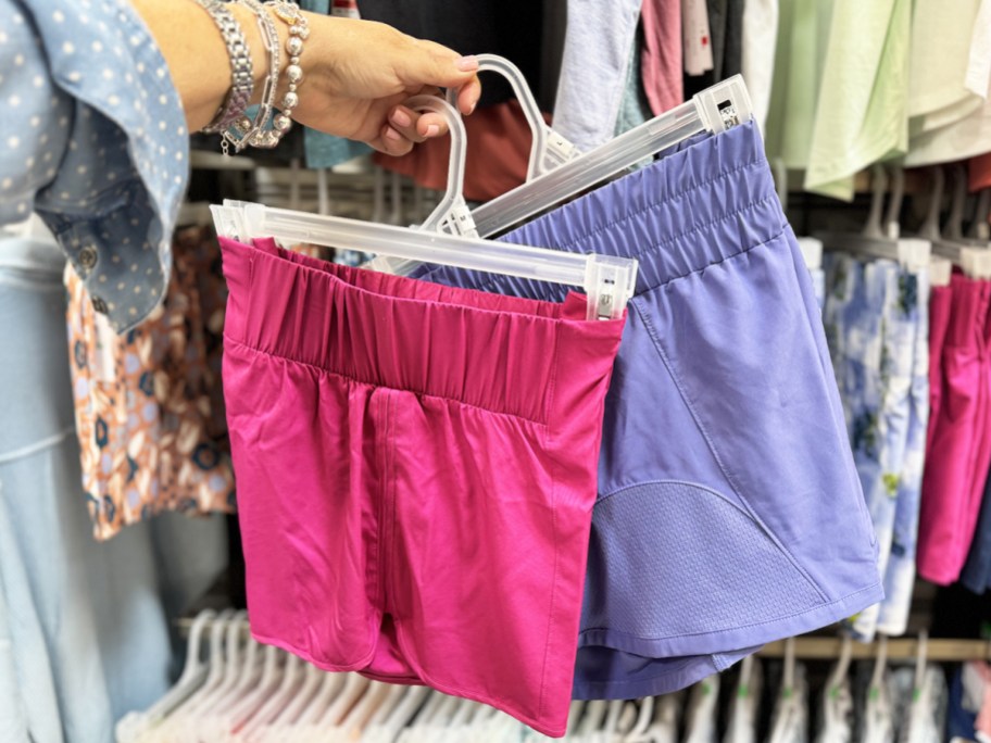 hand holding pairs of pink and purple shorts