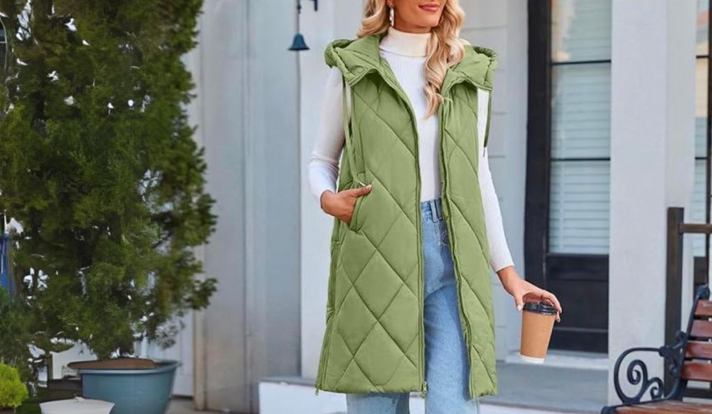 a woman wearing a pea green Hooded Long Puffer Vest on a walk in a town, having a coffee