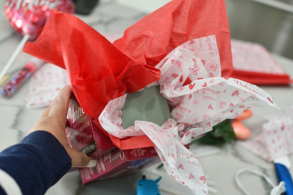adding foam and tissue paper to candy bouquet