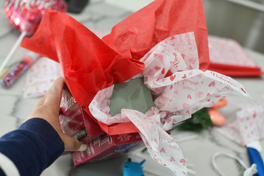 adding foam and tissue paper to candy bouquet