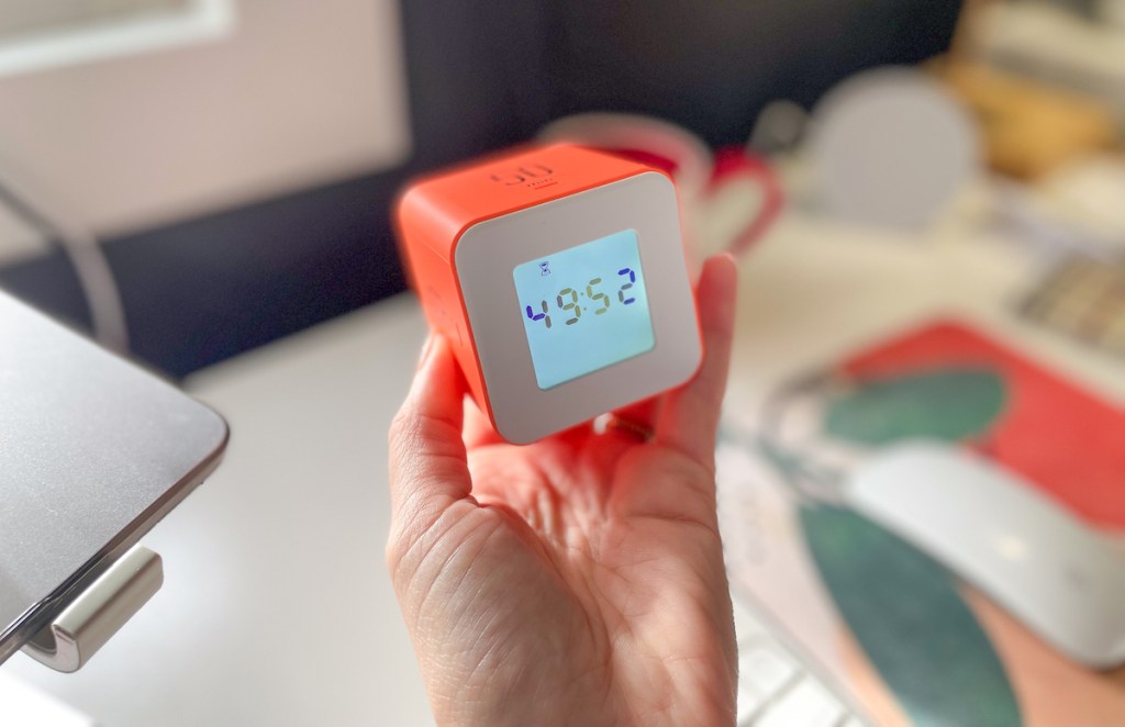 Hand holding an orange cube timer