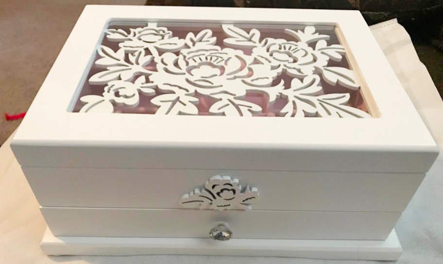white jewelry box with flower carvings on top on table