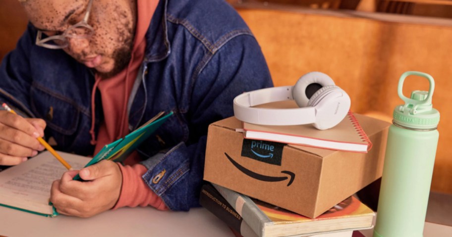 young man studying next to headphones on Amazon Prime box