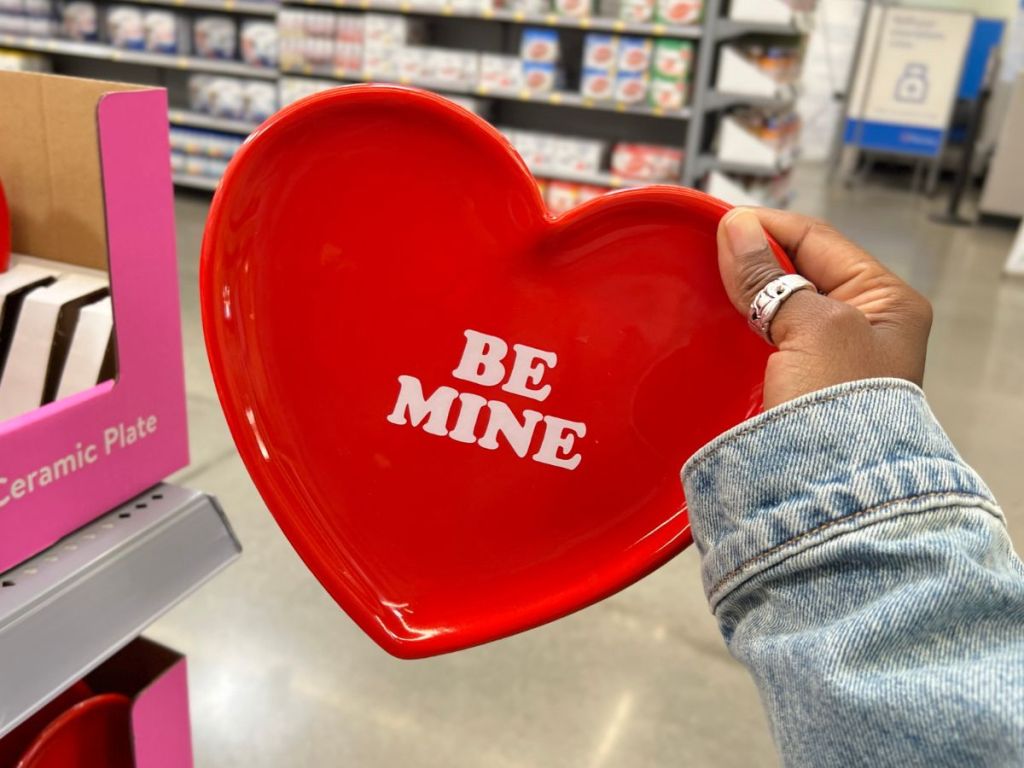 a red heart shaped ceramic serving plate with be mine printed in the middle of the plate